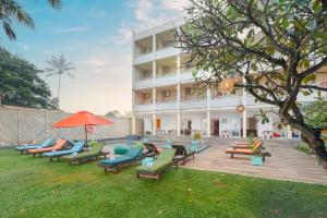 a group of lounge chairs in front of a building at Hotel J Negombo in Negombo