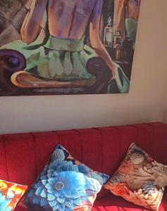 two pillows sitting on a red couch under a painting at Dpto 2D 2B con y sin estacionamiento in Santiago +8 photos