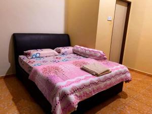 a bedroom with a bed with pink sheets and pillows at Azihar Homestay Marang in Marang