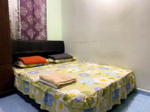 a bed in a room with a flowered table cloth at Azihar Homestay Marang in Marang +1 photo