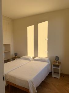 a bedroom with a large white bed with two windows at Casa Rebei Menaggio in Menaggio +8 photos