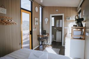 a bedroom with a bed and a desk and a kitchen at Tallarook Hilltop Tiny House 3 by Tiny Away in Tallarook