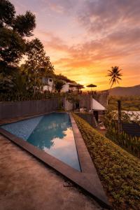 a swimming pool with a sunset in the background at Cempaka Guesthouse in Silebeng