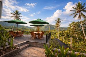 a patio with tables and umbrellas and palm trees at Cempaka Guesthouse in Silebeng