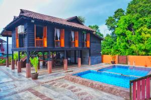 a house with a swimming pool in front of it at Pondok Panglima Awang in Pantai Cenang