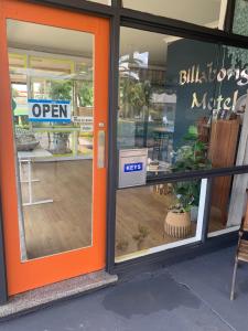 an open door of a building with a sign in the window at Billabong Motel in Gunnedah