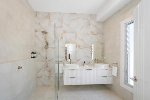 a bathroom with two sinks and a glass shower at 2 Ulmarra in Manning Point +28 photos
