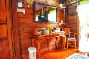 a room with a wooden wall with a table and a mirror at Pondok Panglima Awang in Pantai Cenang