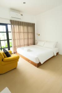 a bedroom with a large bed and a yellow couch at Ban Rub Lom Pool Villa 3 difference villas in Rayong +83 photos