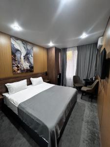 a bedroom with a large bed and a television at AIRIS Residence in Almaty
