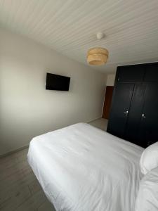 a bedroom with a white bed and a television at Le Panoramique in Saint-Parize-le-Châtel