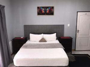 a bedroom with a bed with a butterfly painting on the wall at Black Owl Lodge in Kempton Park +32 photos