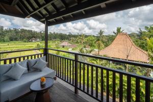 a living room with a couch on a balcony at Emana Abian Taksu in Ubud