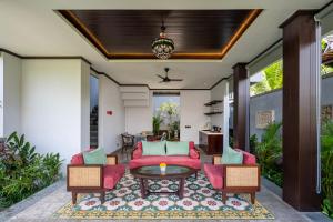 a living room with a red couch and chairs at Emana Abian Taksu in Ubud