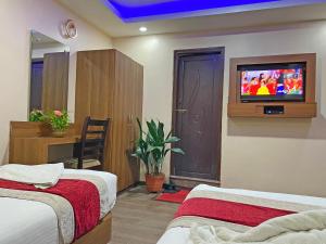 a bedroom with two beds and a tv on the wall at Hotel Maheshwor in Pashupatināth