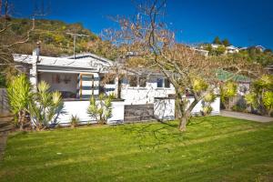 una casa blanca con un patio con césped verde en 3 & 4 Bedroom Holiday Houses Central Picton en Picton