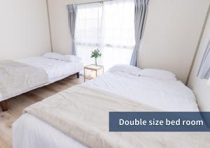 two beds in a room with a double size bed room at The Emu Park Tomiyoshi in Kanie