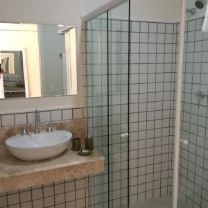 um banheiro com pia e box de vidro em Passagem da Neblina - Bed & Breakfast em Campos de Jordão