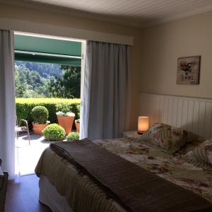 a bedroom with a bed and a large window at Passagem da Neblina - Bed & Breakfast in Campos do Jordão