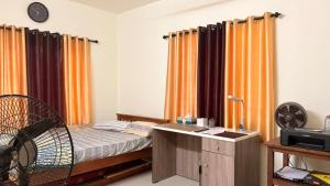 a bedroom with a bed with orange curtains and a desk at Casa Areca in Cheruthuruthi
