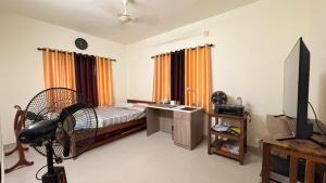 a bedroom with a bed and a desk and a television at Casa Areca in Cheruthuruthi