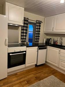 a kitchen with white cabinets and a black stove top oven at The house in Vika in Lødingen