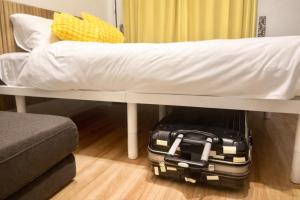 a suitcase under a bed with a white sheet at UPHouse 2C Gotokuji in Tokyo