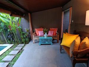 a porch with two couches and a table on a patio at Sanur Backpacker Room Bali in Sanur