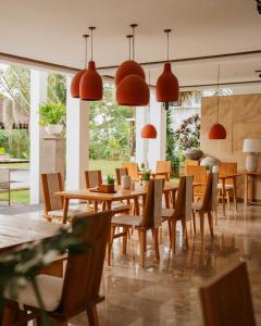 a restaurant with wooden tables and chairs and pendant lights at Bumi Kinar Heritage in Ubud