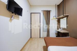 a room with a bed and a television on the wall at Hotel Gandamanah Mitra RedDoorz in Bekasi