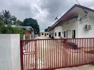a red fence in front of a white house at Rugani Homestay in Papar