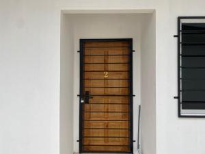 a brown wooden door in a white wall at Rugani Homestay in Papar