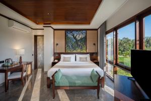 a bedroom with a bed and a desk and a television at Emana Abian Taksu in Ubud +38 photos