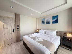 a hotel room with a large white bed and a door at Indigo Hotel Hatyai 2 Khet 8 in Sathani Hat Yai