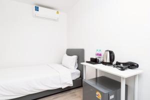 a room with a bed and a table with a microwave at Rest Inn Silom - BTS Chong Nonsi in Bang Rak