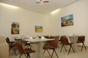 uma sala de jantar com mesas e cadeiras e pinturas na parede em Pousada Três Pescadores em Búzios