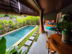 a swimming pool in a room with a table and a bed at Sanur Backpacker Room Bali in Sanur