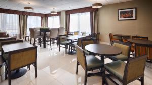 un comedor con mesas, sillas y ventanas en Best Western O'Hare/Elk Grove Hotel, en Elk Grove Village