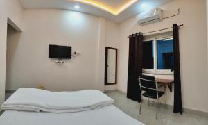 a bedroom with a bed and a table and a tv at Swastiik Inn in Belpahār