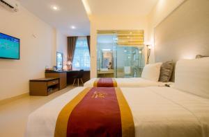 a hotel room with two beds and a desk at Smile Hotel in Hanoi