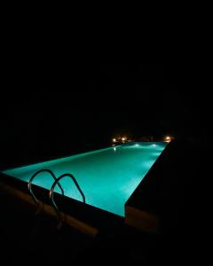 ein Swimmingpool bei Nacht mit zwei Stühlen daneben in der Unterkunft Vanaswara in Kolad