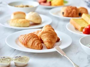 a table with plates of croissants and other pastries at Park Central Sakura Hotel in Osaka