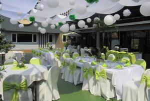 a room with white tables and chairs with green bows at The Corporate Inn Hotel in Manila