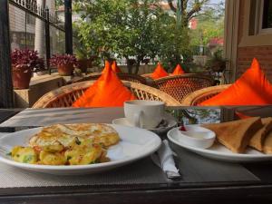 a table with two plates of eggs and potatoes and toast at Butsugen in Kathmandu