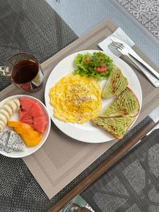 a breakfast plate of eggs and toast and a bowl of fruit at La Petite Maison Luang Prabang in Luang Prabang