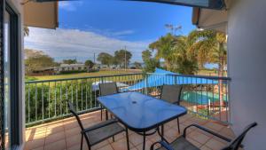 uma varanda com mesa e cadeiras e uma piscina em Dolphin Waters em Tin Can Bay