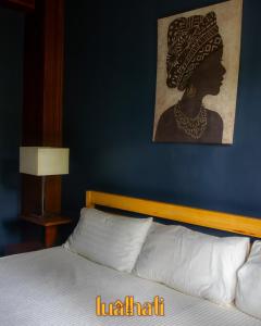 a bedroom with a bed with a painting on the wall at Lualhati Homestay in Baguio