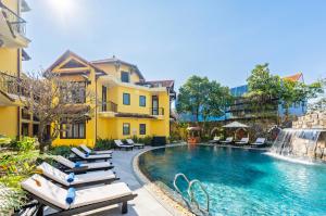 a pool at a resort with lounge chairs and a waterfall at Lantern Boutique Hoi An in Hoi An