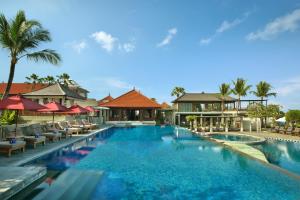 una piscina en un complejo con sillas y sombrillas en Bali Niksoma Boutique Beach Resort, en Legian