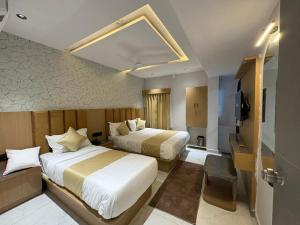 a hotel room with two beds and a television at Hotel Pine Lake in Ahmedabad